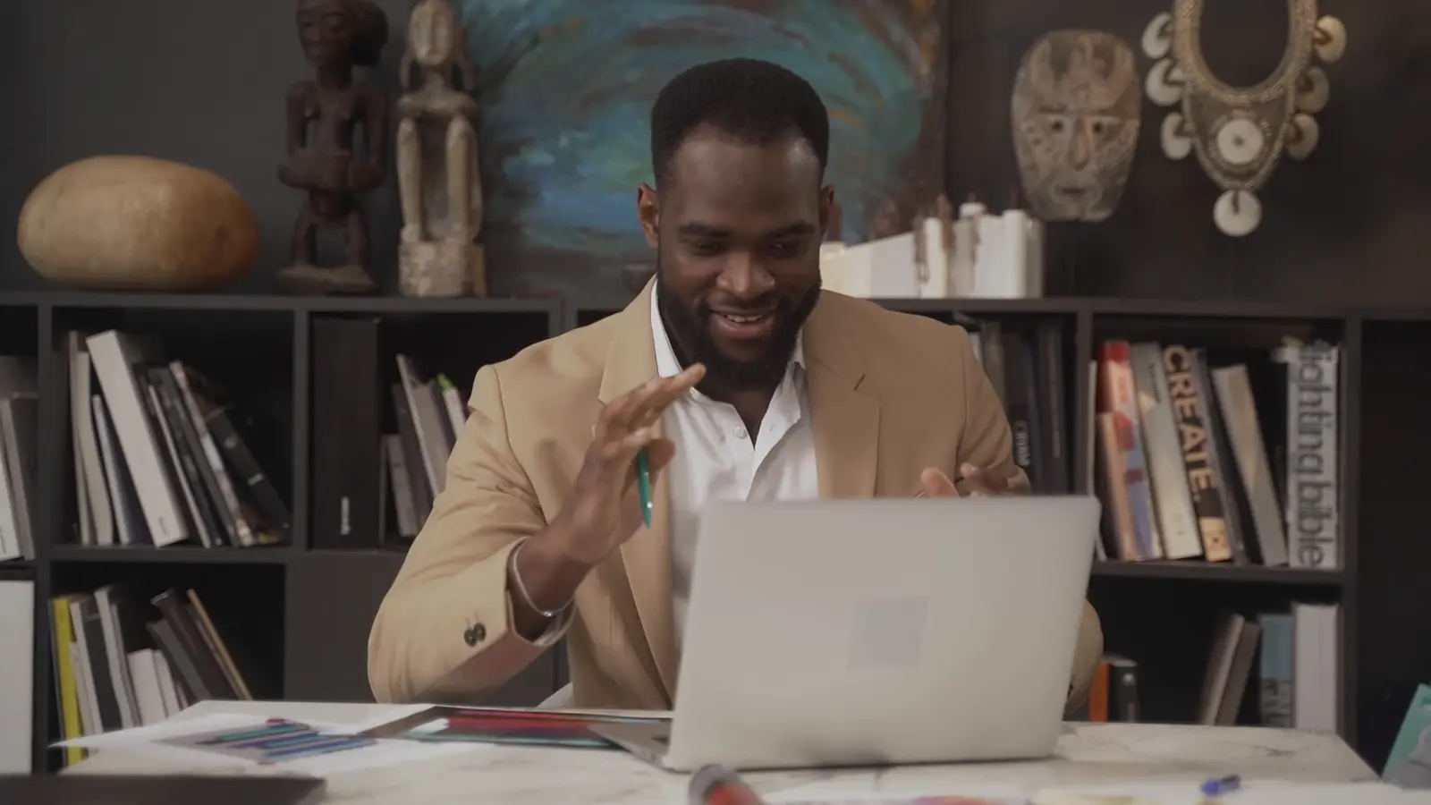 A man in a beige jacket laughing during a video call