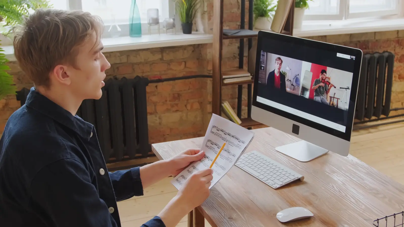A young man holding his notes during a video call at his desk