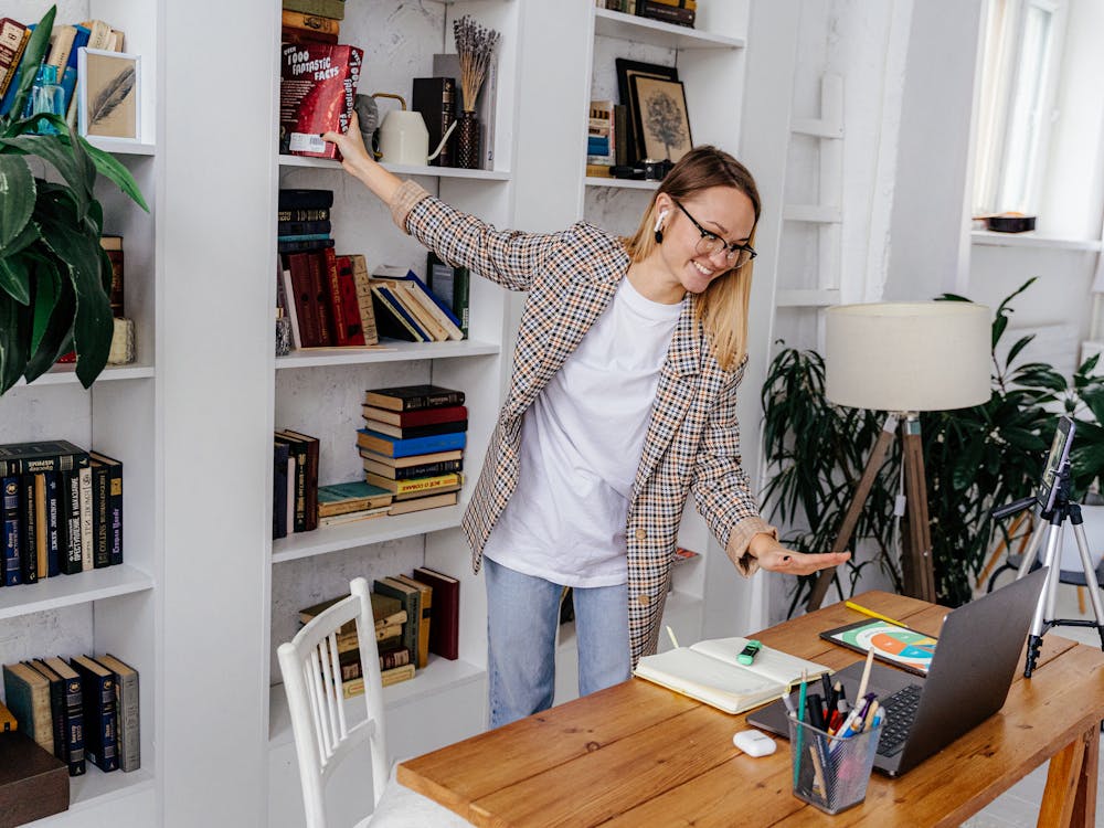 A woman laughing during an animated video call at her home desk.
