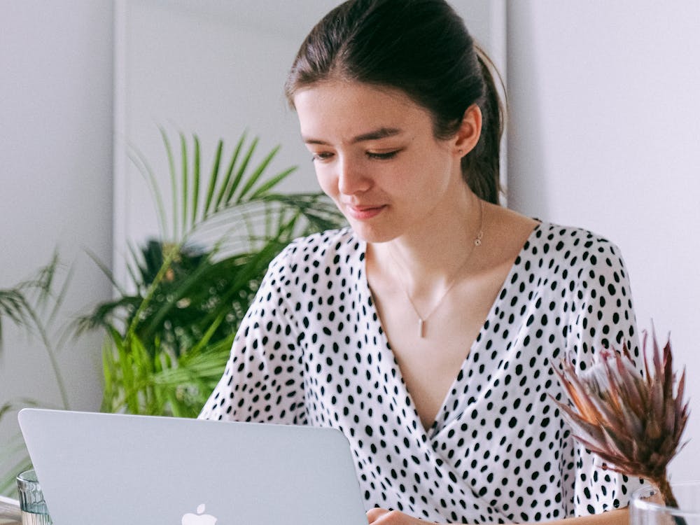 A woman working calmly at her laptop surrounded by plants.