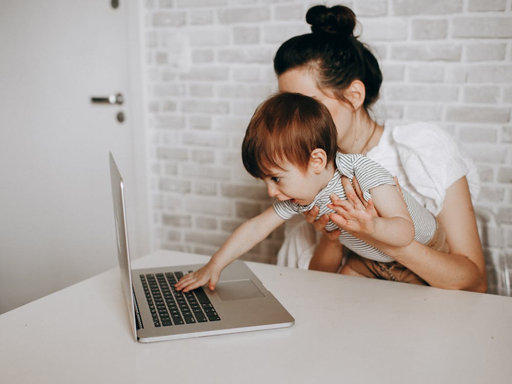 A mother and her young child looking at a laptop together at home.