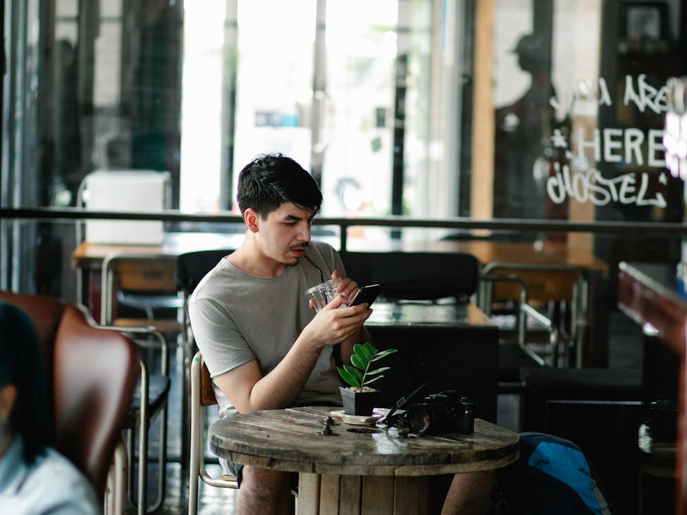 A traveller checking their phone at a hostel café table.