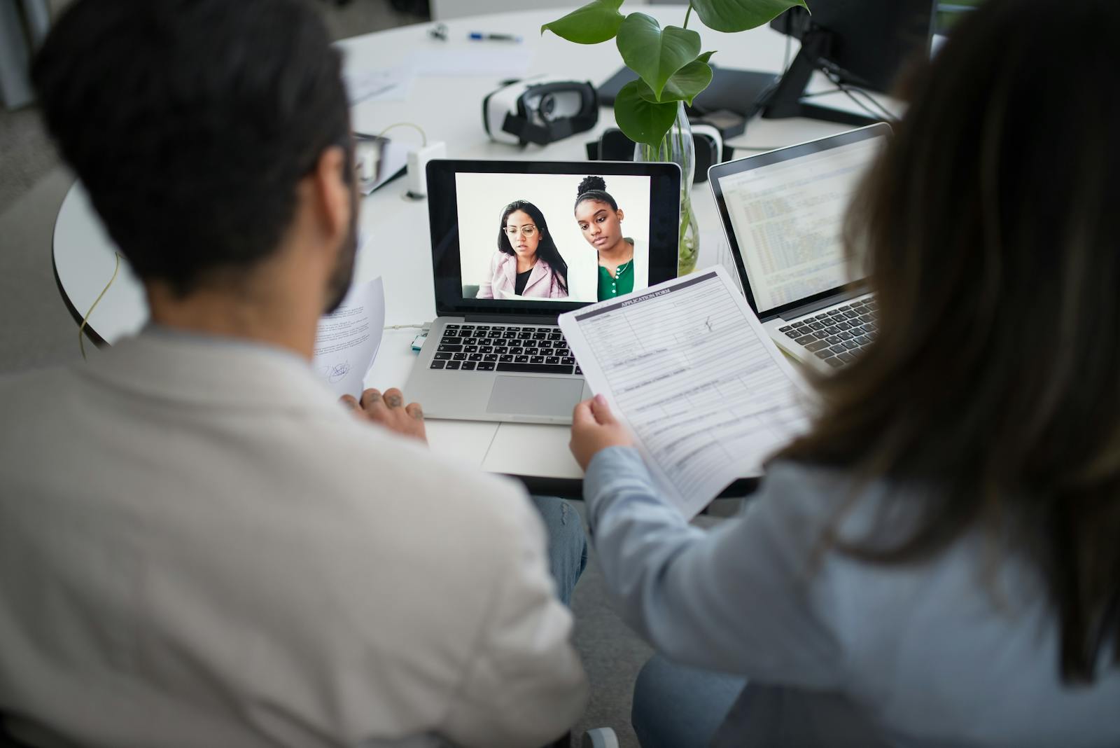 Two professionals in a virtual job interview using laptops in a modern office.